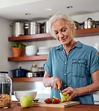 Woman with dentures cutting up fruit